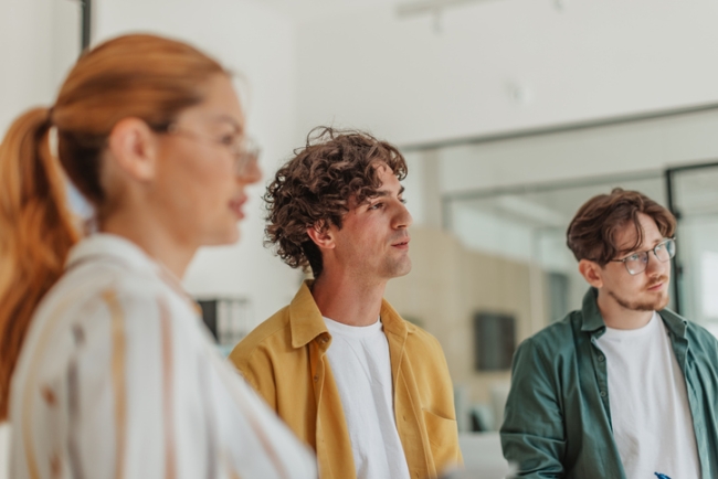Employees collaborate in a modern office space while discussing their work on a project together.