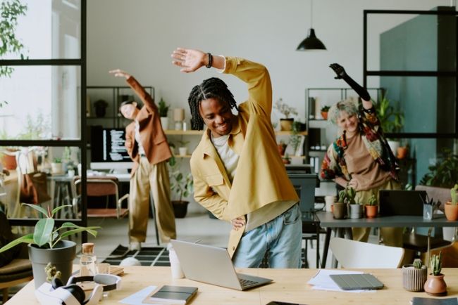 Group of young coworkers doing morning exercise in a modern office.