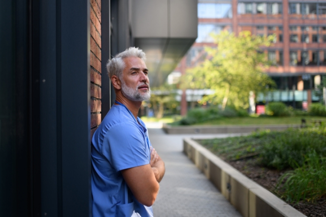 Healthcare worker outside hospital wearing medical scrubs.
