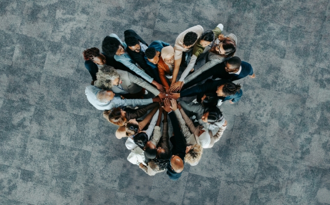A group of people standing in a heart formation, symbolizing unity, teamwork, and collaboration.