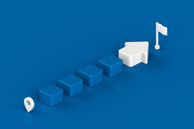 Sequential blue block leading to white arrow and flag, symbolizing step by step journey to reach goal.
