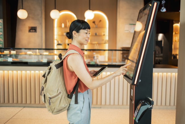 Tourist using self ordering kiosk in cafe.