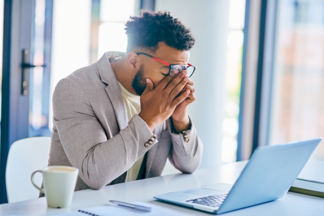 Young employee suffering from burnout in a modern office.