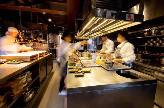  Hectic cooks working in a busy commercial kitchen at a restaurant.