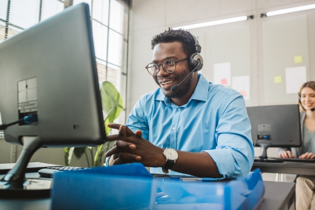 Friendly man in call center service talking with costumers by headset.