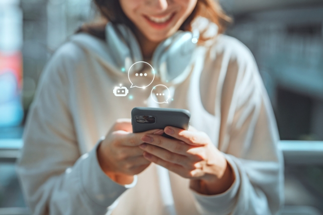 Happy young Asian woman using mobile smartphone with AI chatbot for customer service.