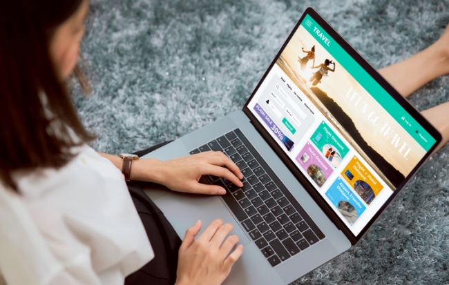 Woman sitting in her house with using laptop and booking flight travel search ticket holiday and hotel on website.