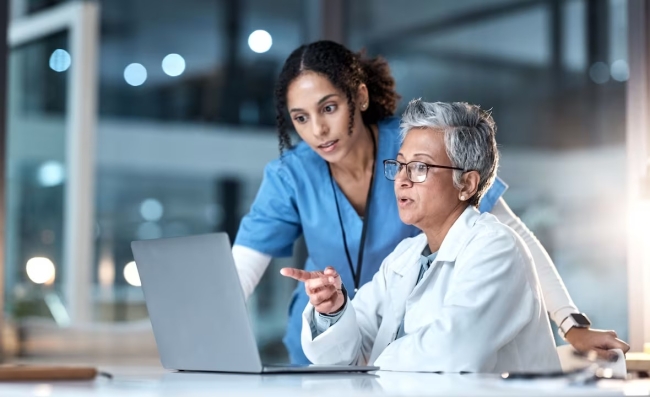 Two healthcare workers looking at a laptop together