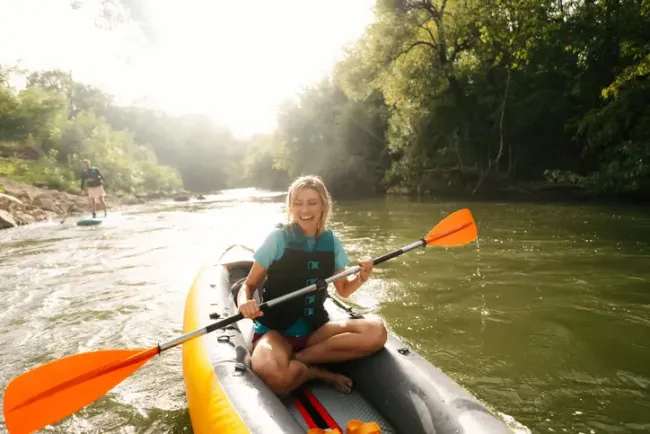 Happy young woman kayaking on the river.