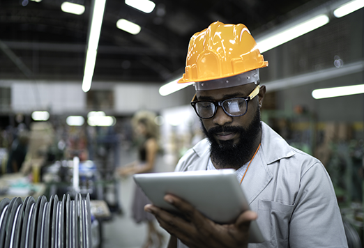 Employee with hard hat looking at tablet device.