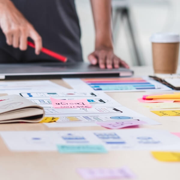 Close up ux developer and ui designer brainstorming about mobile app interface wireframe design on table with customer brief and color code at modern office.Creative digital development agency