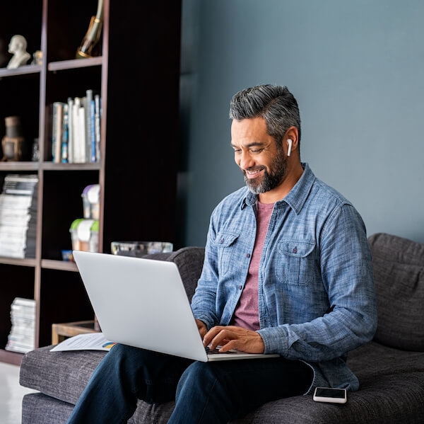 Indian man typing on laptop while working from home