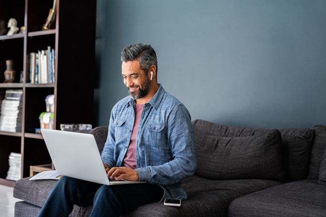 Indian man typing on laptop while working from home