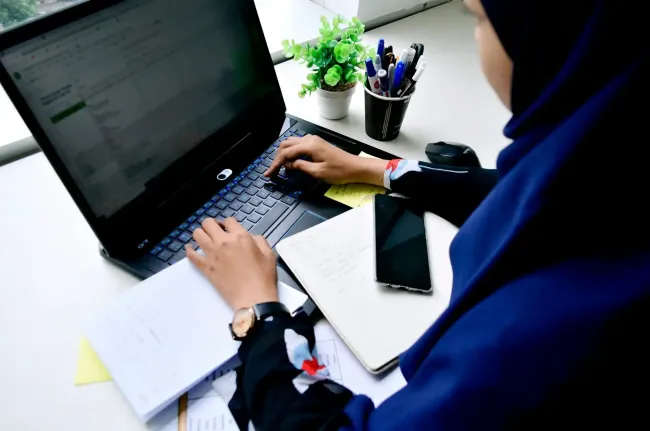 person in blue long sleeve shirt using a laptop to conduct market research with AI