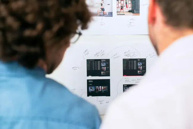 Two men facing a white board with boxing images