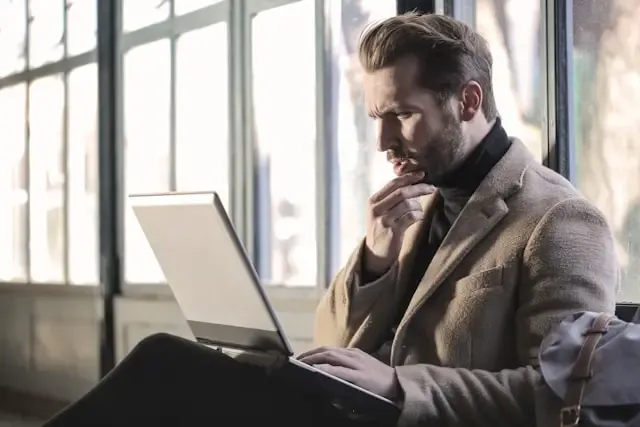 Male customer on laptop thinking about their next purchase.