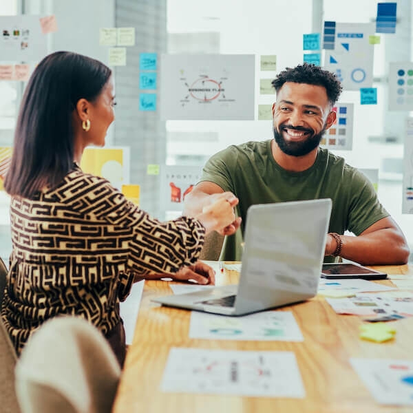 Two happy employees shaking hands