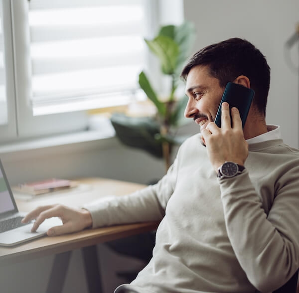Man smiling on phone and computer