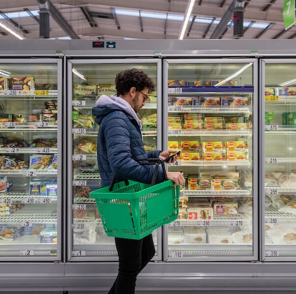 Man standing in an isle looking at prices of different products