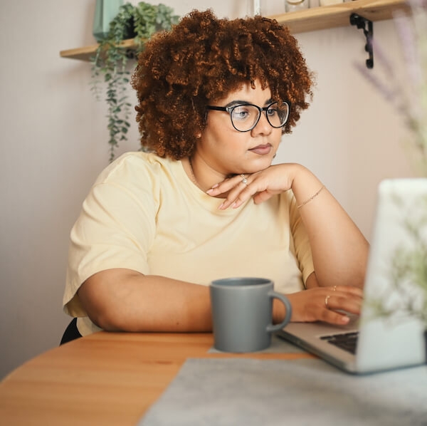 Stylish plus size Black woman working on computer at home office.