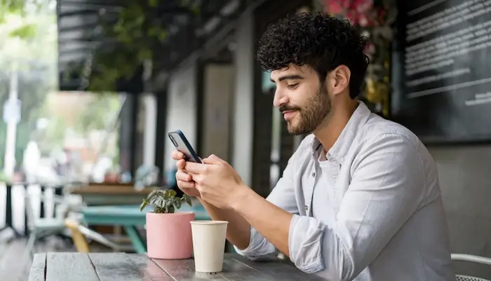 Person sitting down at a table using their phone