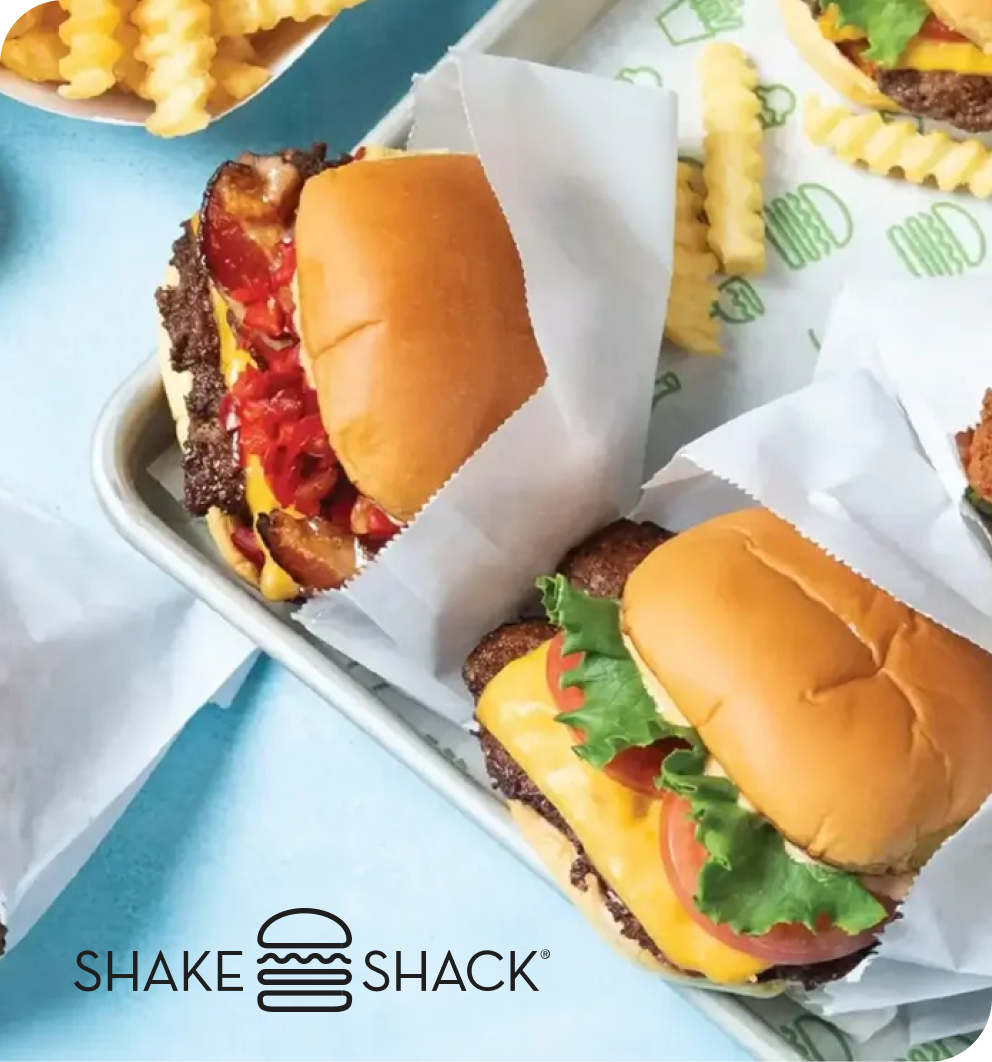 Shake Shack burgers and crinkle-cut fries served on a tray with branded wax paper.