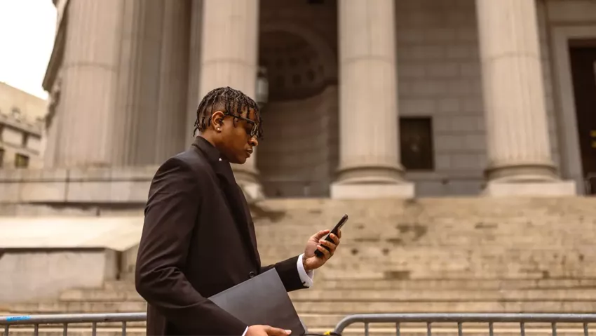 A man scrolls through his phone while walking outside a federal building.